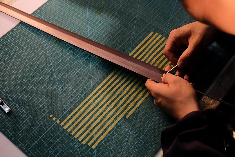 剣の塗装準備：グリットパターンを形成するためクレープ紙を貼っている様子